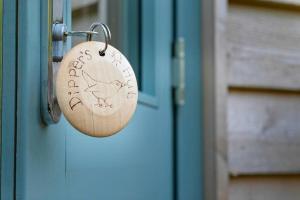 a padlock on a door with a bird written on it at Dipper's Hut - Luxury Shepherds Hut with Hot Tub in Blakeney