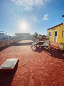 dos sillas sentadas en un suelo de tierra con el sol en el fondo en Casa Lolo, en La Oliva