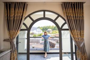 a woman standing on the balcony of a house at Thung Lũng Xanh TQK Hotel in Da Lat