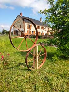 a large metalwheel in the grass in front of a house at La Brousse Kacha in Malleret-Boussac