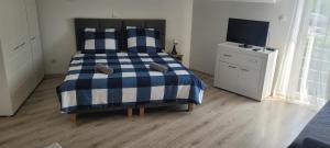 1 dormitorio con 1 cama azul y blanca y TV en Pokoje Gościnne Marusa en Szczytno