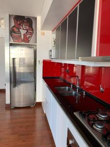 cocina con armarios rojos y nevera de acero inoxidable en Luxury Apartment V. López en Vicente López
