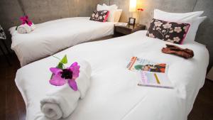 two beds in a hotel room with towels and a magazine at Full Circle Apartments in Kutchan