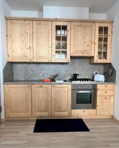 a kitchen with wooden cabinets and a stove at Pizzo Stella - appartamento con box in Campodolcino
