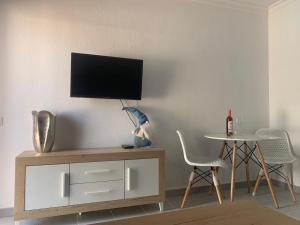 salon ze stołem i telewizorem na ścianie w obiekcie Danubio Studio Playa del Inglés w mieście Maspalomas