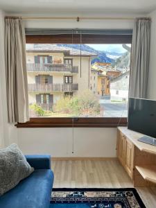 salon z niebieską kanapą i dużym oknem w obiekcie Pizzo Stella - appartamento con box w mieście Campodolcino