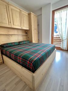 a bedroom with a wooden bed with a plaid blanket at Pizzo Stella - appartamento con box in Campodolcino