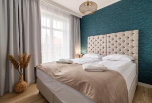 a bedroom with a white bed with a blue wall at Sopot Marina Beachside Residence in Sopot