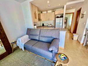 a living room with a blue couch and a kitchen at Condado de alhama NARANJOS 8 SV/92 in El Romero
