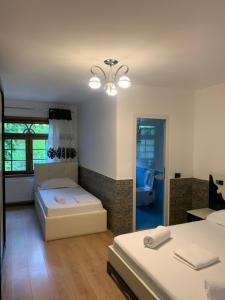 ein Schlafzimmer mit 2 Betten und ein Badezimmer in der Unterkunft Fusha e Gjes Hotel in Valbonë