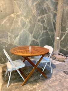 una mesa de madera y 2 sillas junto a una pared de piedra en Departamento Las Heras en Mendoza