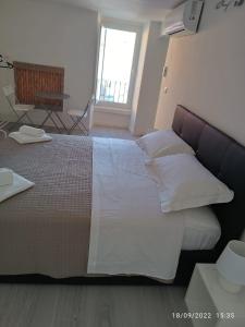 - une chambre dotée d'un grand lit avec des draps et des oreillers blancs dans l'établissement Di Fronzo Guest House T, à Triggiano