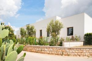 una casa blanca con valla y cactus en Lisetta Gardens Boutique & Suites, en Cisternino