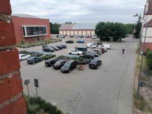a parking lot with cars parked in front of a building at Przytulne Mieszkanko Centrum in Mrągowo