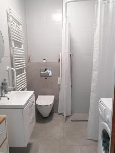 a white bathroom with a toilet and a shower at Przytulne Mieszkanko Centrum in Mrągowo