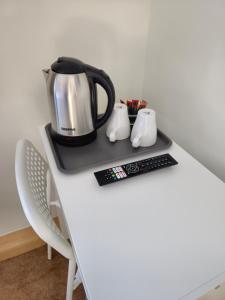 a coffee pot on a table with a remote control at Homefield Lodge in London