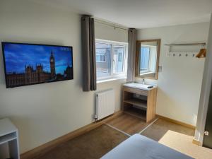 a bedroom with a tv on the wall and a window at Homefield Lodge in London
