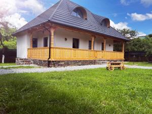 a large house with a large deck on a grass field at La Bunici in Vişeu de Sus