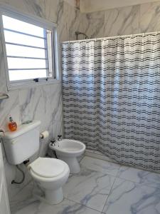 uma casa de banho com um WC e uma cortina de chuveiro em La Gloria em Deán Funes