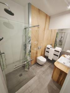 ein Bad mit einer Dusche, einem WC und einem Waschbecken in der Unterkunft M&K Apartament Magiczny Las, Gdańsk - Wyspa Sobieszewska in Danzig