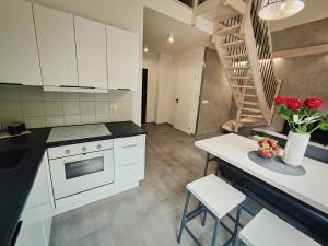 a kitchen with white cabinets and a table with roses at M&K Apartament Magiczny Las, Gdańsk - Wyspa Sobieszewska in Gdańsk