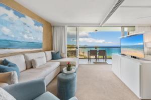 ein Wohnzimmer mit einem Sofa und einem großen TV in der Unterkunft Oceanfront Mana Kai 2 bedroom condo in Wailea