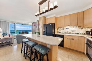 una cocina con una gran isla con taburetes de bar en Oceanfront Mana Kai 2 bedroom condo en Wailea