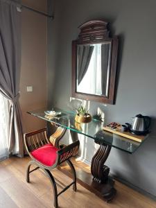 uma mesa de vidro com uma cadeira vermelha e um espelho em Erythros Hotel em Cesme