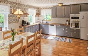 una cocina con armarios grises y una mesa con sillas. en Pet Friendly Home In Valdemarsvik With Wifi en Valdemarsvik