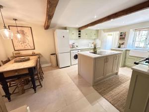 a kitchen with a table and a white refrigerator at Charming 3-Bed Cottage near Chipping Norton in Chipping Norton