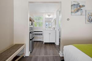 a small kitchen with white cabinets and a bed in a room at Pelham on Earle in West Harwich