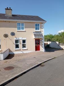 uma casa com uma porta vermelha numa rua em Castlebaldwin Country Residence em Sligo