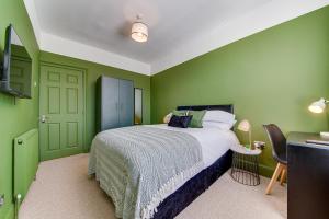 a bedroom with green walls and a bed and a table at Air Host and Stay - Rockfield Lodge, sleep 12 free parking next to LFC in Liverpool