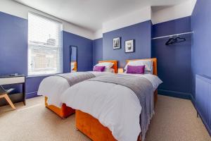 two beds in a bedroom with blue walls at Air Host and Stay - Rockfield Lodge, sleep 12 free parking next to LFC in Liverpool