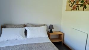 1 cama con almohadas blancas y mesita de noche con lámpara en Quinta Paúl de Baixo en Guimarães