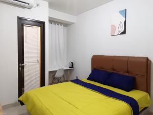 a bedroom with a bed with a yellow and blue blanket at Transpark Cibubur By Arsakha Property Management in Kalimanggis