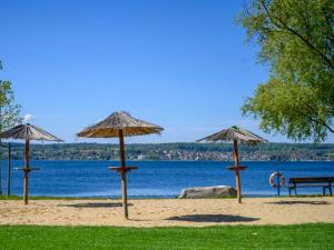 einen Strand mit Sonnenschirmen und einer Bank neben dem Wasser in der Unterkunft Villa Melanie in Überlingen