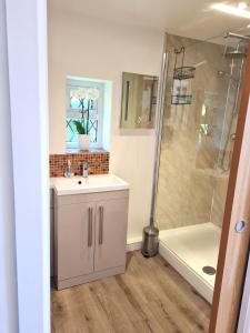 a bathroom with a sink and a shower at Topsy-Turvy, Gardeners Cottage, Clungunford, Ludlow, Shropshire SY70PN in Broome