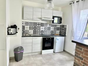 a kitchen with white cabinets and black and white tiles at T2 climatisé au cœur du pôle Aéronautique,à 8 minutes de l'aéroport in Colomiers