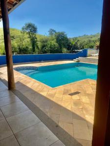una piscina de agua azul en un patio en Pousada Girassol 2, en Poços de Caldas