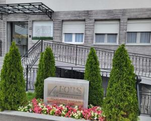 a sign in front of a building with trees and flowers at ForS Resort & Spa in Belgrade