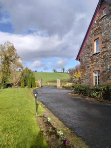 a road next to a stone building with a house at Rossclare Lodge in Enniskillen