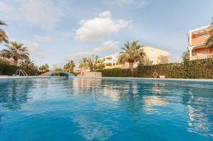 une grande piscine bleue avec des palmiers et des bâtiments dans l'établissement Guayaba, à Dénia