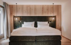a bedroom with a large bed with white sheets and pillows at Hotel Oberforsthof in Sankt Johann im Pongau