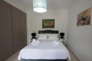 a bedroom with a white bed with two towels on it at Met & Kas corner spacious house with countryard in Volos