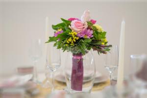 a vase filled with flowers on a table with glasses at Studio apartman Lenox in Rijeka