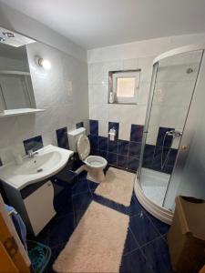 e bagno con servizi igienici, lavandino e doccia. di Apartament centru a Râmnicu Vâlcea