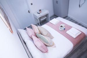 sypialnia z białym łóżkiem z poduszkami i stołem w obiekcie Harrow Luxury flat With free parking. w Londynie