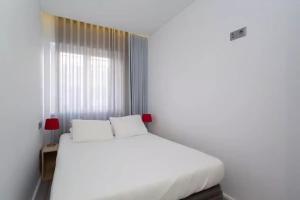 uma cama branca num quarto com uma janela em Bright Lisbon T2 with 35 m2 Terrace, 2bed and 2bath and fast internet! em Lisboa