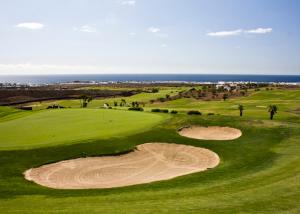 a view of a golf course with the ocean in the background at El Pisito La Dolce Vita in Puerto del Carmen